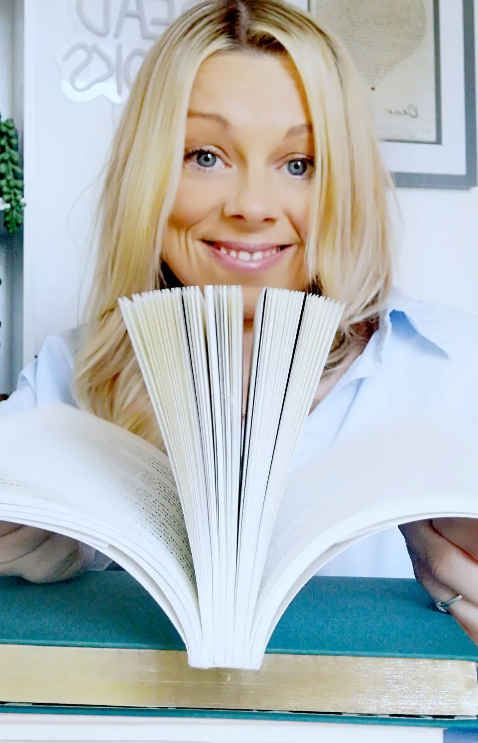 Katie smiling behind the pages of an open book